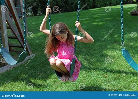 Lovely Little Girl At Swings In The Park With Pink Dress During Summer