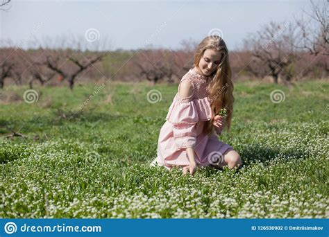 Blonde Woman In Pink Dress Walks In The Garden And Gathers Flowers