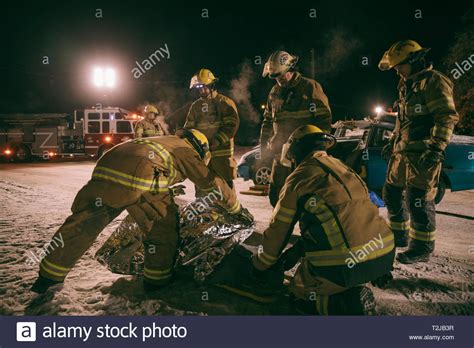 Firefighters Tending To Victim At Scene Of Car Accident Stock Photo Alamy