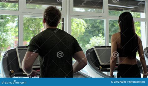 Close Up Woman And Man Running On Treadmill At The Gym Back View Of