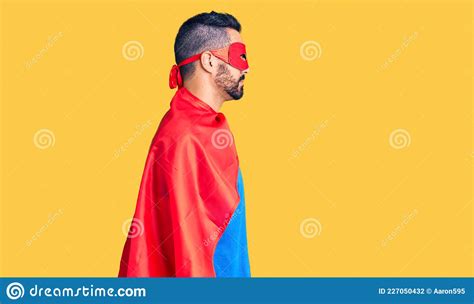 Young Hispanic Man Wearing Super Hero Costume Looking To Side Relax