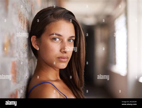 Youthful Confidence Cropped Portrait Of An Attractive Young Woman Leaning Against A Face Brick