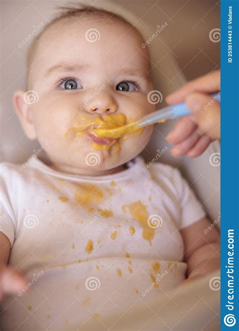 Happy Baby Eating Porridge And Smiling In High Chair Stock Image