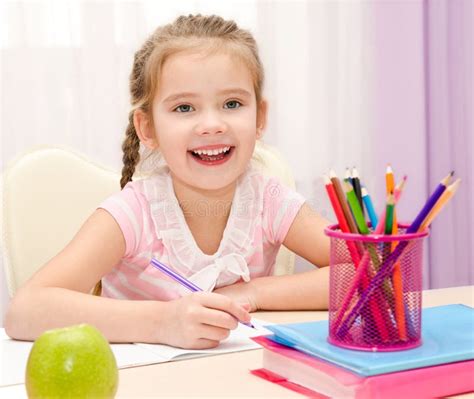 Cute Little Girl Is Writing At The Desk Stock Photo Image Of Person