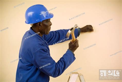 african american construction worker handyman carpenter standing on ladder working with