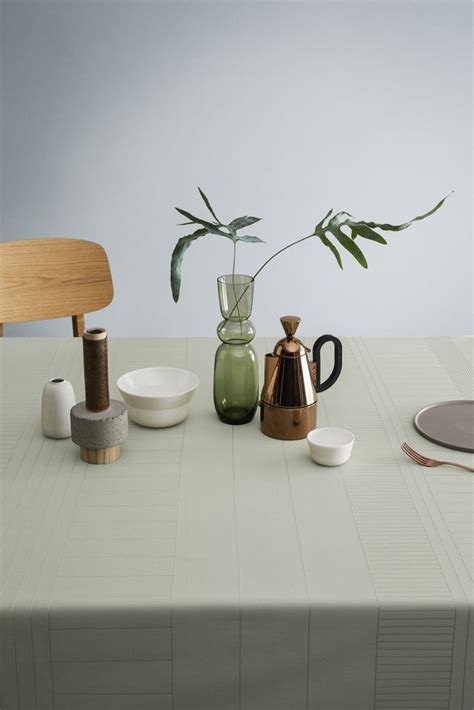 A Table Topped With Plates And Cups Next To A Vase Filled With A Green