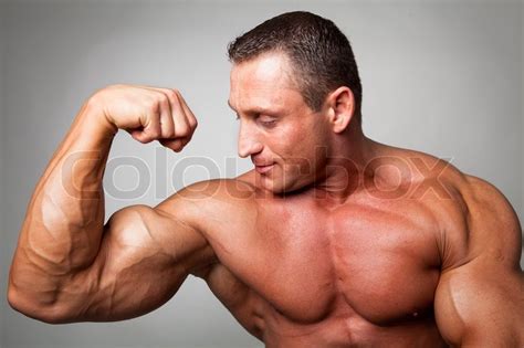 Muscular Man Flexing His Biceps On Gray Stock Photo Colourbox