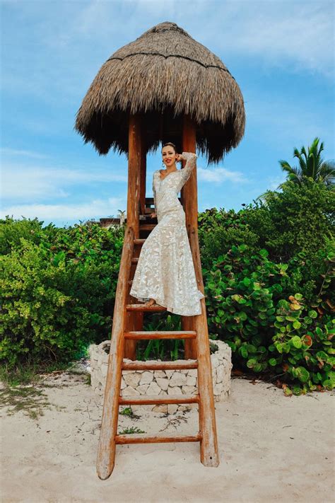 A Woman In A White Dress Is Standing On A Wooden Ladder And Posing For