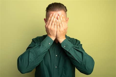 Free Photo Young Handsome Man In Green Shirt Covering Face With Arms