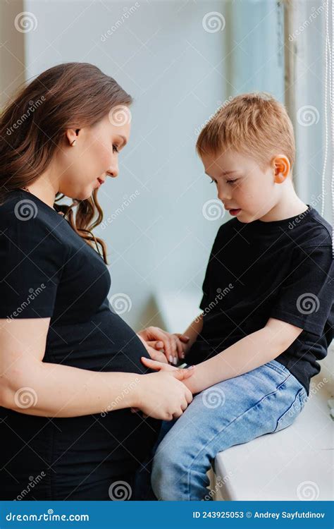 A Pregnant Mother And Son In Black Clothes By The Window Stock Image
