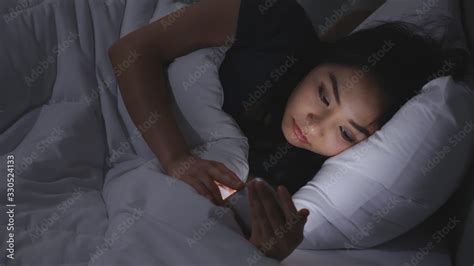 Asian Babe Woman Lying On Bed Play Smartphones During Night Time In Bedroom That Turns Off