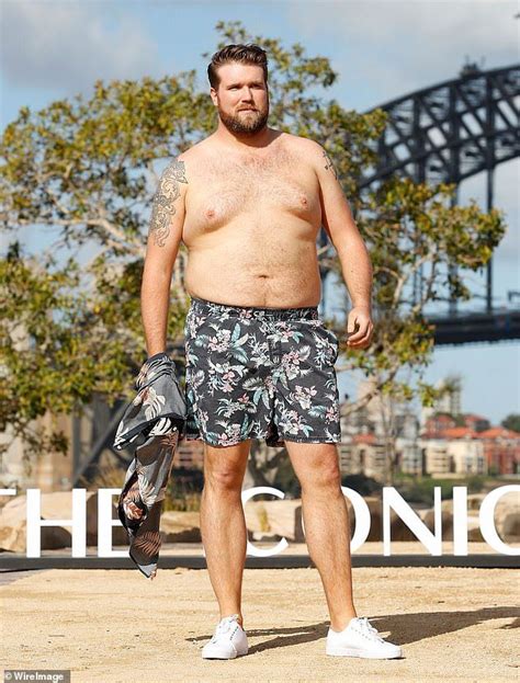 A Man With No Shirt On Standing In Front Of The Sydney Bridge And
