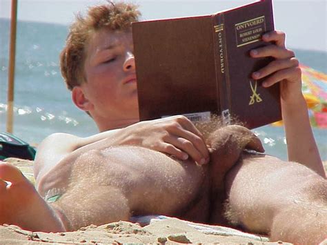 PELADOS EM PÚBLICO NA PRAIA E COM AMIGOS Nudista concentrado na leitura na praia