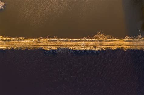 Drone View Of Dirt Road Between Different Color Water Stock Photo