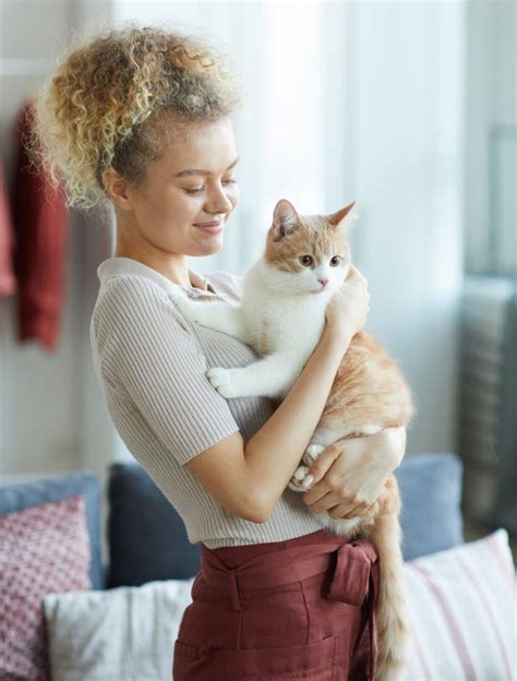 A Woman Holding A Cat In Her Arms
