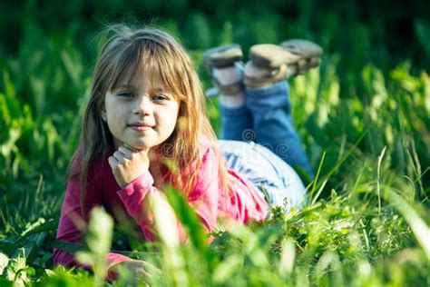 Portrait Of Little Girl Lying On A Meadow In The Grass Stock Photo