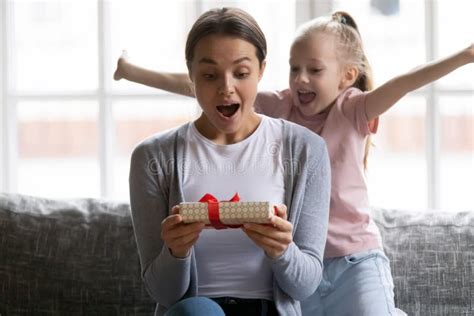 Excited Daughter Girl Giving Birthday Gift Box To Amazed Mom Stock