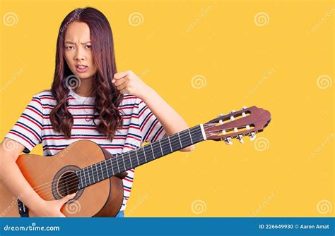 Young Beautiful Chinese Girl Playing Classical Guitar Annoyed And