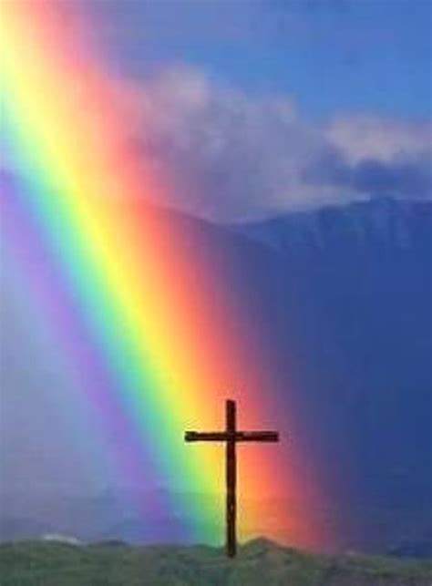 A Cross On Top Of A Hill With A Rainbow In The Sky And A Bible Verse