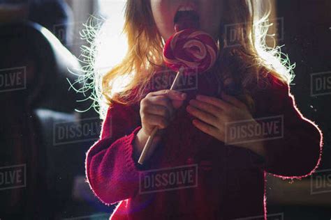 Midsection Of Girl Eating Lollipop At Home Stock Photo Dissolve