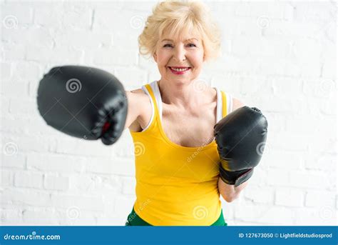 Happy Senior Woman In Boxing Gloves Training And Smiling Stock Photo