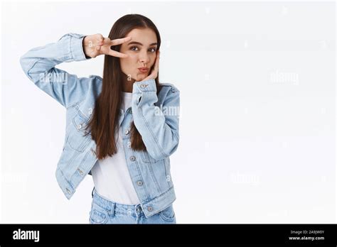 Coquettish Feminine Good Looking Brunette Woman In Denim Outfit Showing Peace Or Victory Sign