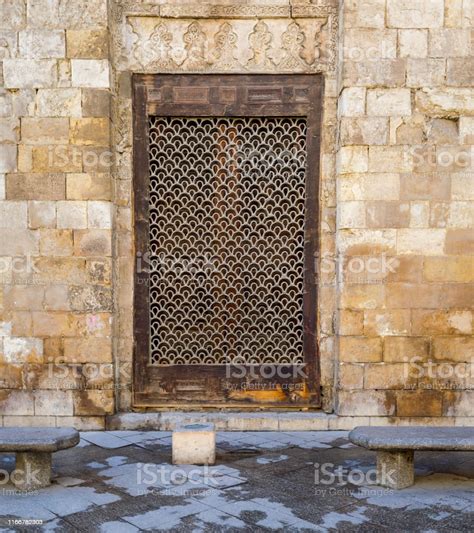 Wooden Grunge Window With Decorated Iron Grid Over Stone Bricks Wall