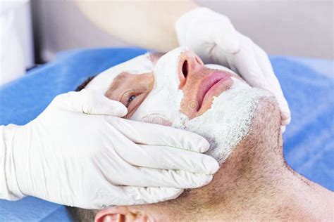 Man Does The Procedure Cleaning His Face With A Clay Mask In The Beauty
