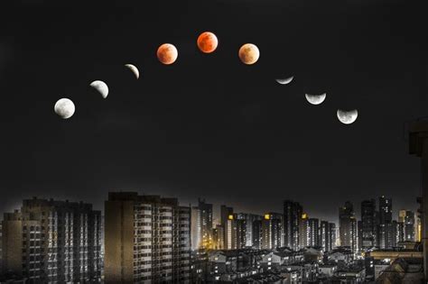 White And Red Moon Over Lighted High Rise Buildings During Night Time