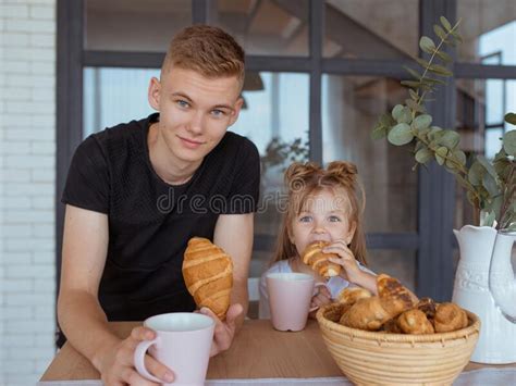 portrait of adorable beautiful caucasian siblings brother and sister having breakfast drinking