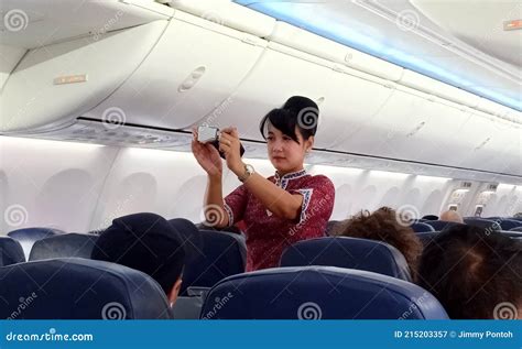 a female flight attendants on the aisle show passengers about safety instruction on board with