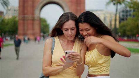 Two Happy Mixed Race Women Friends Making Selfie Outdoors And Choosing Best Photo On Mobile
