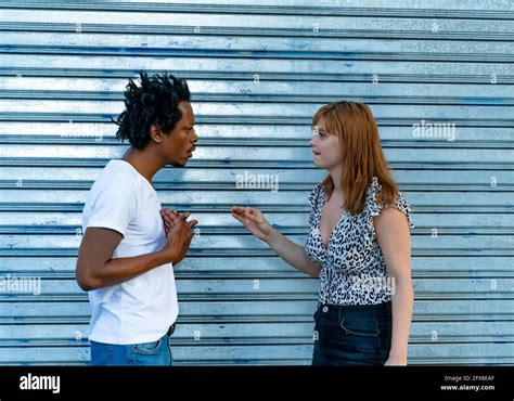 Unhappy Mixed Race Couple Arguing On The Street Front Of A Metal