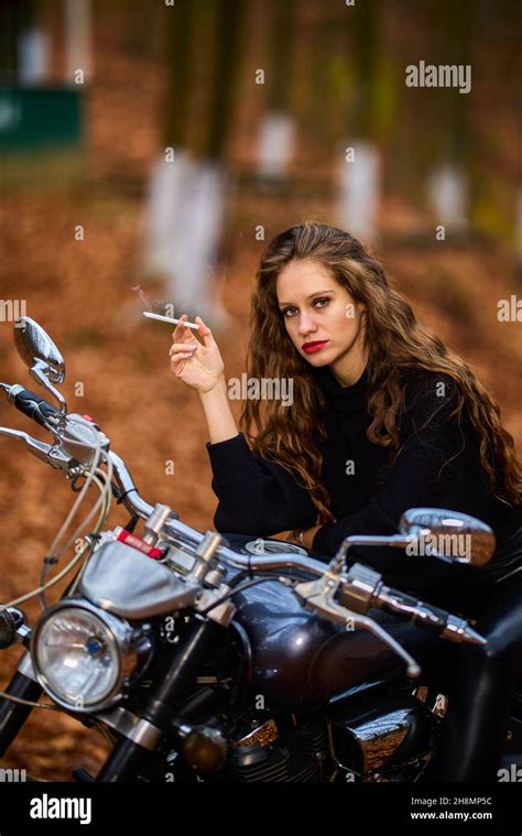 A Beautiful Long Haired Woman Smoking On A Chopper Motorcycle In Autumn