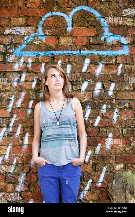 Teenage Girl Standing In Front Of Brick Wall With Graffiti Hi Res Stock