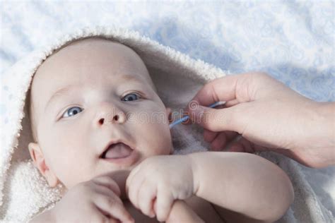 Mother Cleaning Ear With Cotton Swab To Her Baby Boy Stock Image