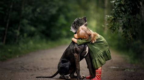 Cute Baby Girl Is Hugging A Dog Wearing Green Dress And