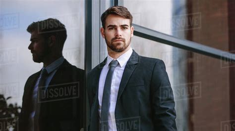 Portrait Of Handsome Young Businessman Standing By Office Building And