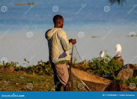 African Fisher Man On The Lake Shore Near Boat Preparing The Net For