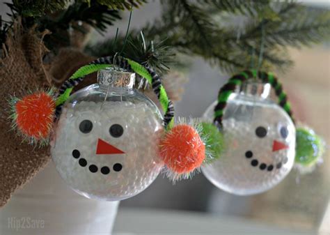 Three Snowman Ornaments Are Hanging From A Christmas Tree With Green