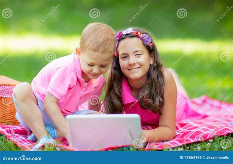 Sister And Brother Lying Down On Blanket And Using Laptop Stock Image