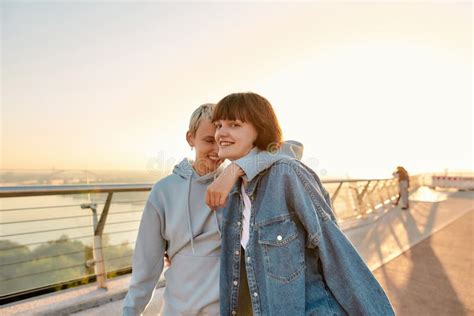 lesbian couple smiling walking on the bridge and hugging while watching the sunrise together