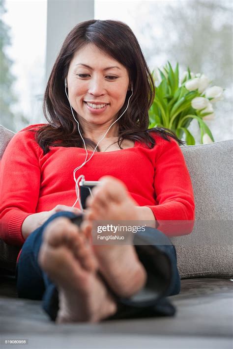 Woman With Bare Feet On Sofa Listening To Mp3 Player Photo Getty Images