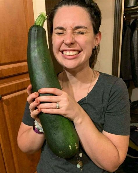 A Woman Holding A Large Cucumber In Her Hands