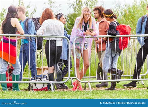 Group Of Young Friends Waiting Behind Barrier At Entrance To Music