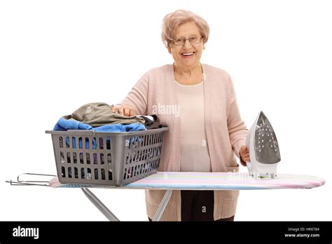 Happy Mature Woman Behind An Ironing Board With A Laundry Basket Full