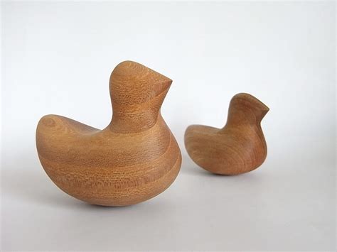 Two Wooden Birds Sitting Next To Each Other On A White Surface