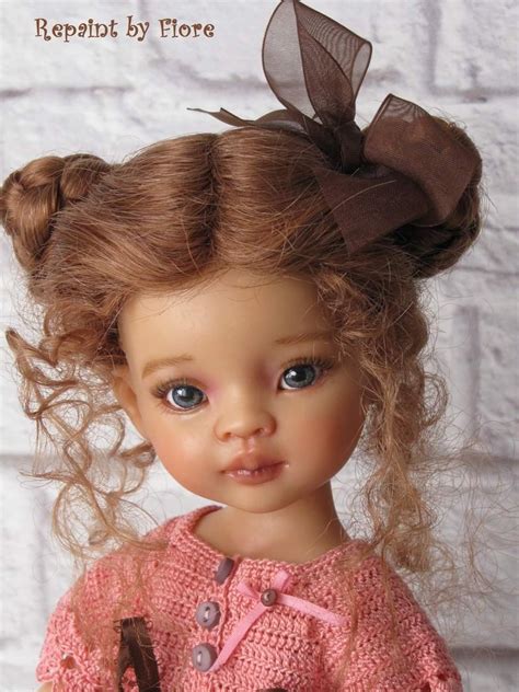 A Close Up Of A Doll Wearing A Pink Sweater With A Brown Bow On Her Head