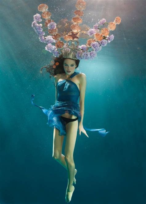 A Woman In A Blue Dress Under Water With Flowers On Her Head And Hair