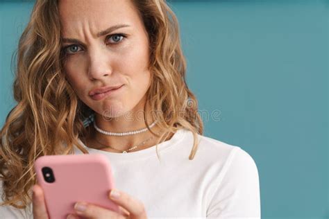 Blonde Puzzled White Woman Looking At Camera While Using Smartphone